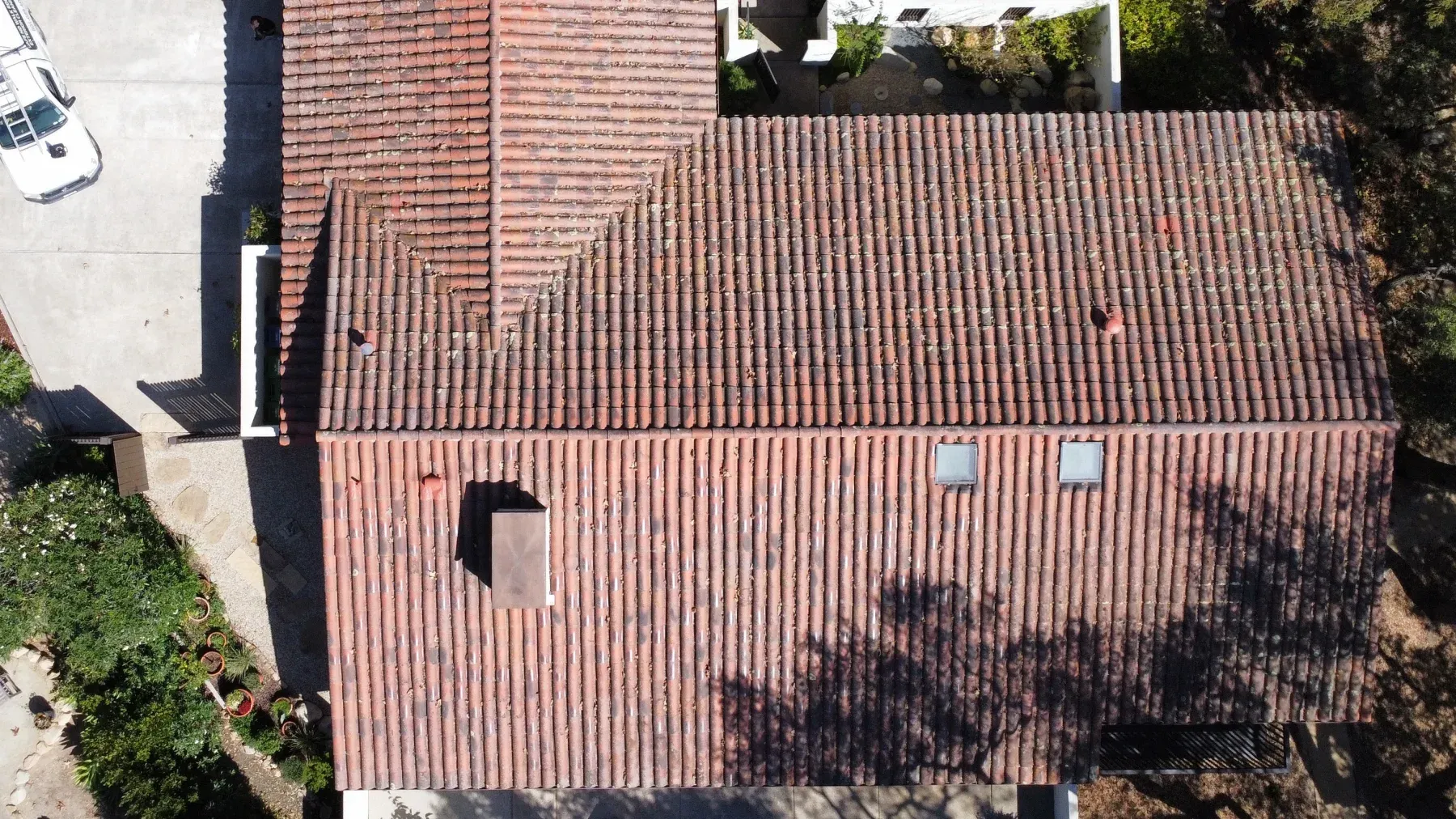 Drone view of a Santa Barbara clay tile roof before soft washing, tiles darkened with moss and lichen